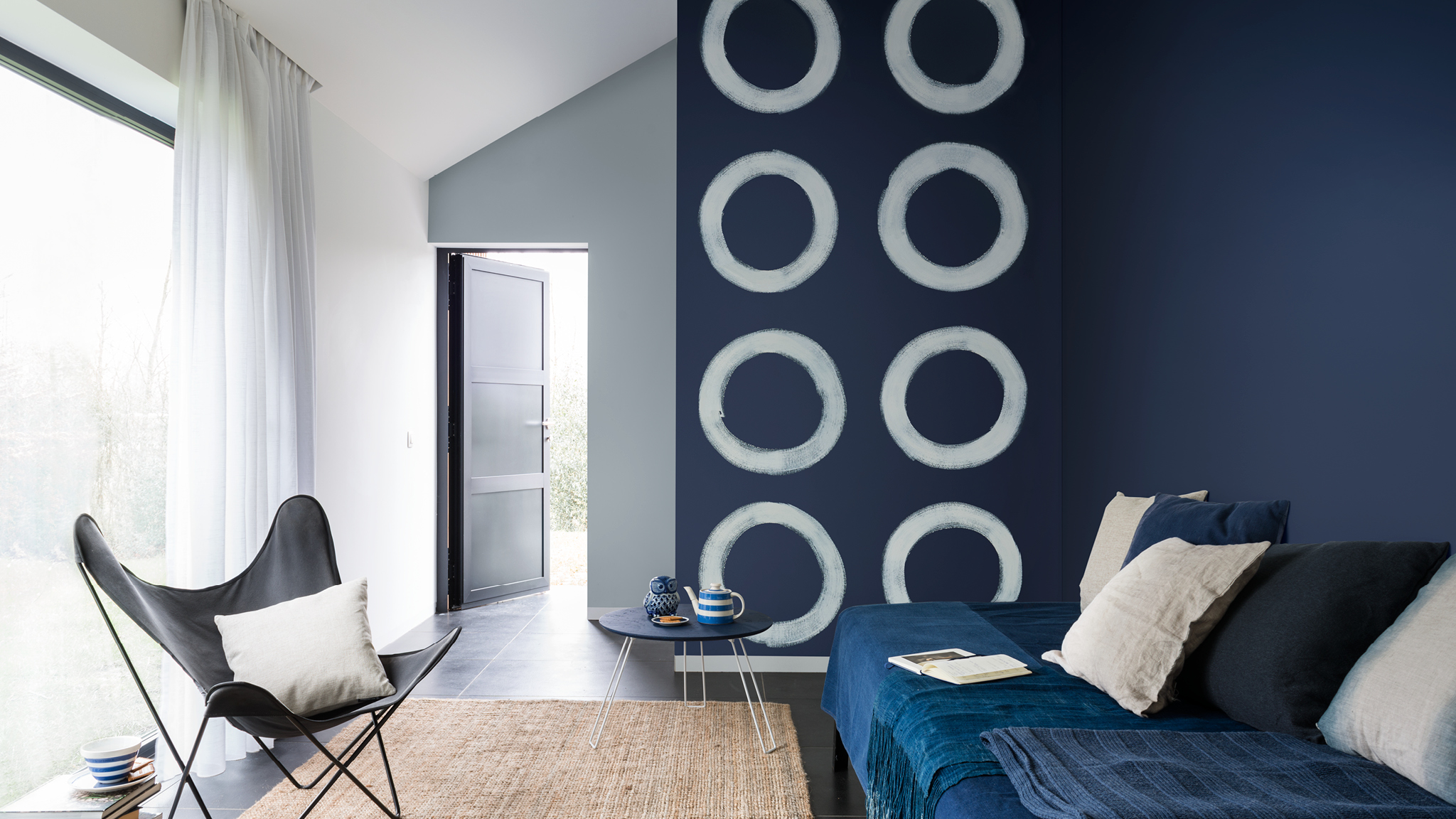 Wand mit blauen Kreisen Die auflockernde Wirkung von freihändig gezeichneten Formen kann Ihrem Zuhause eine dynamische Kreativität verleihen.